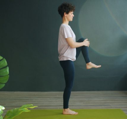 Attractive female adult is doing yoga in wellness studio balancing on one leg relaxing enjoying recreational activity. Modern people, sports and relaxation concept.